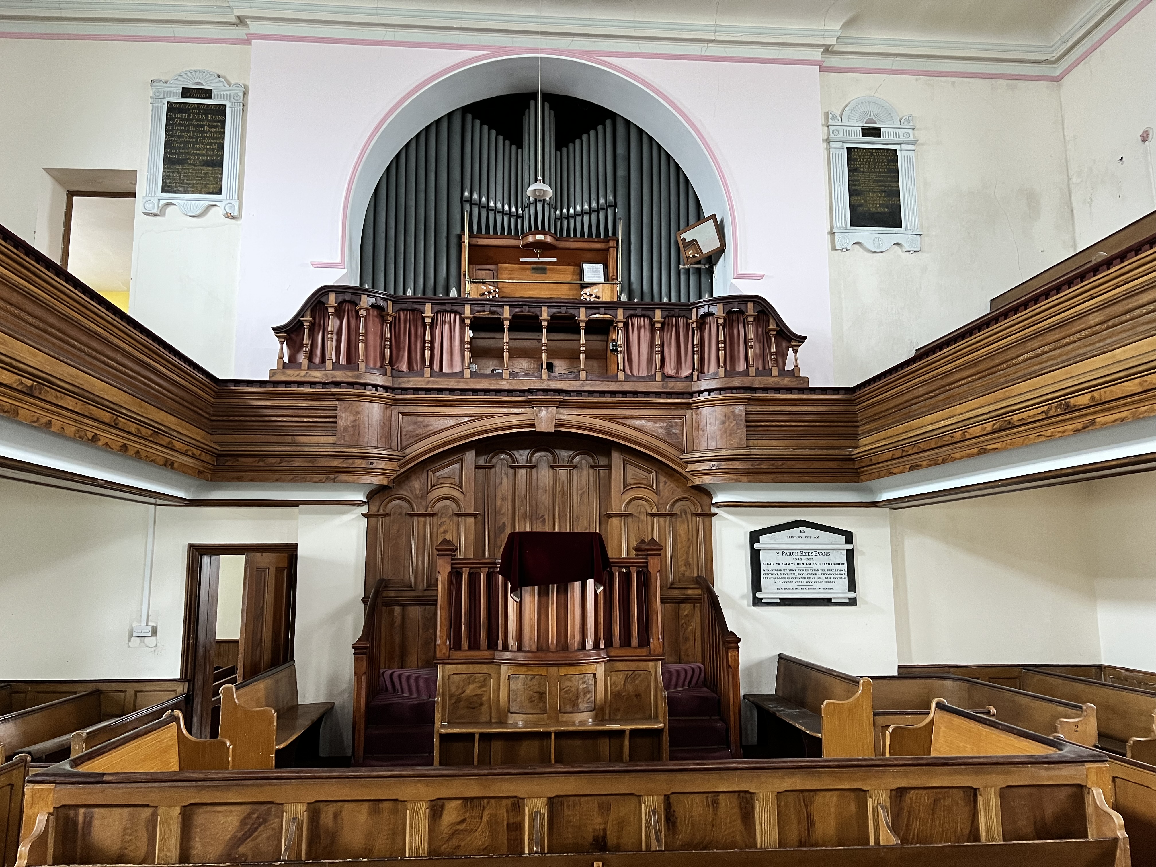 Inside the chapel: carved wooden pulpit, pipe organ, curved balcony and original box pews